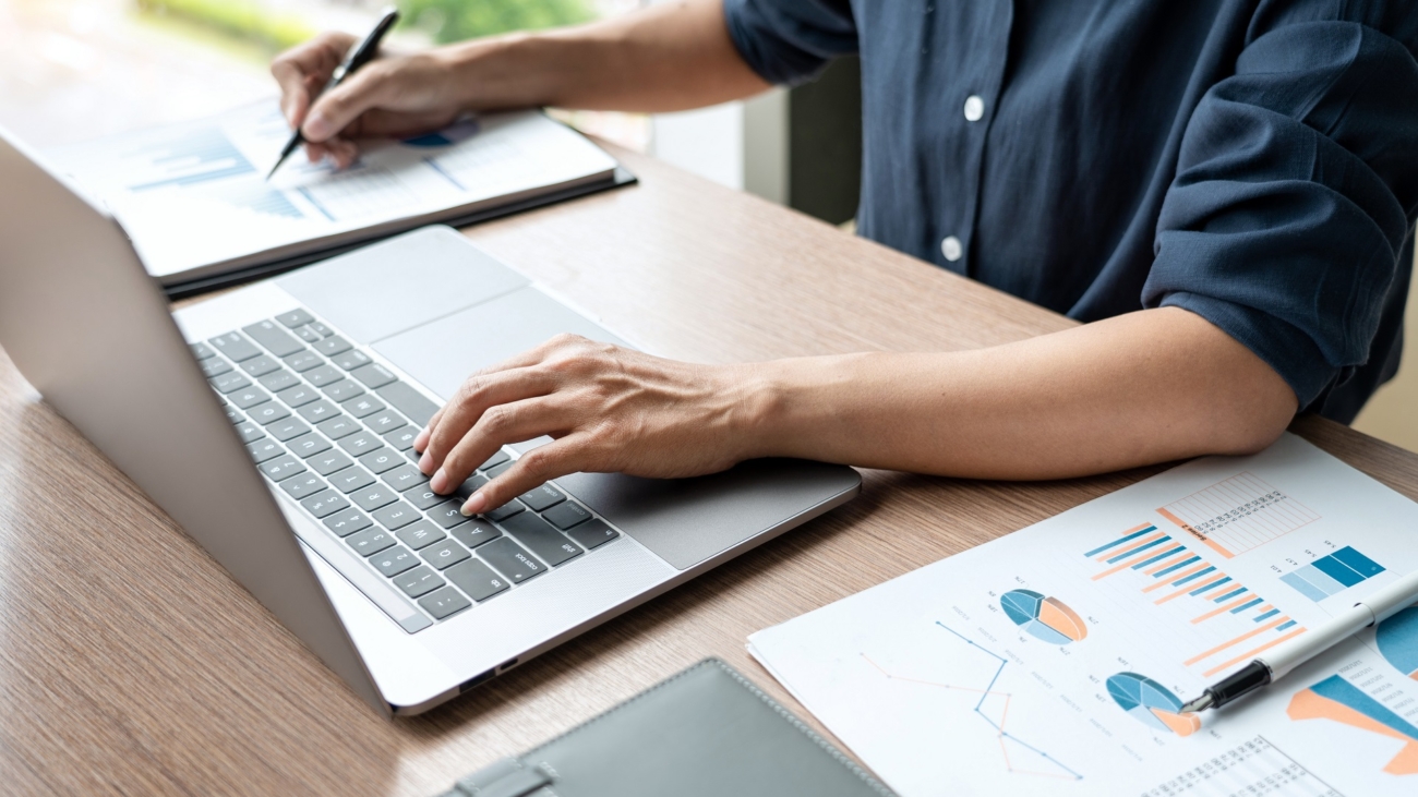 Business man working with graph data in laptop and documents on his desk at office